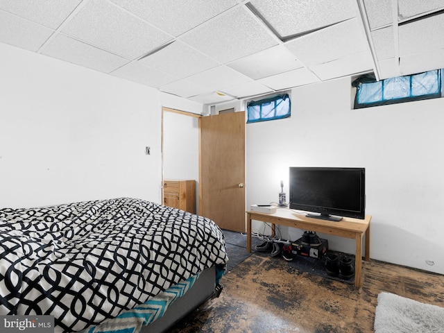 bedroom with concrete floors and a paneled ceiling