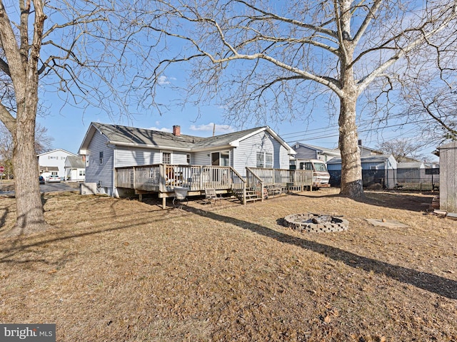 back of house with a fire pit, a chimney, a wooden deck, and fence