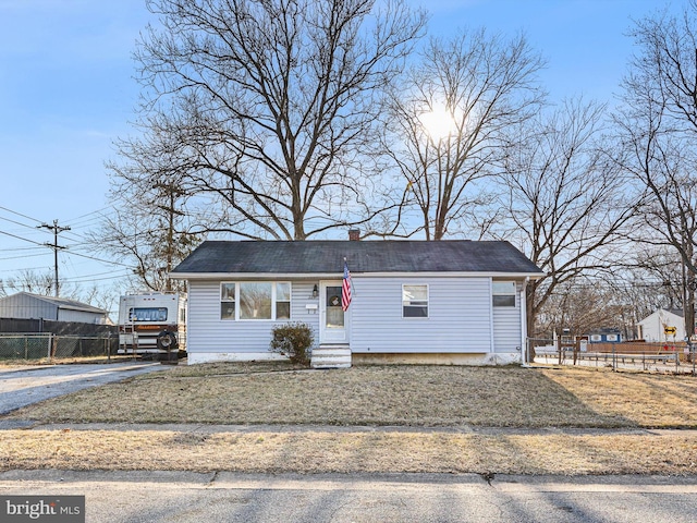 view of front facade featuring entry steps, aphalt driveway, a chimney, and fence