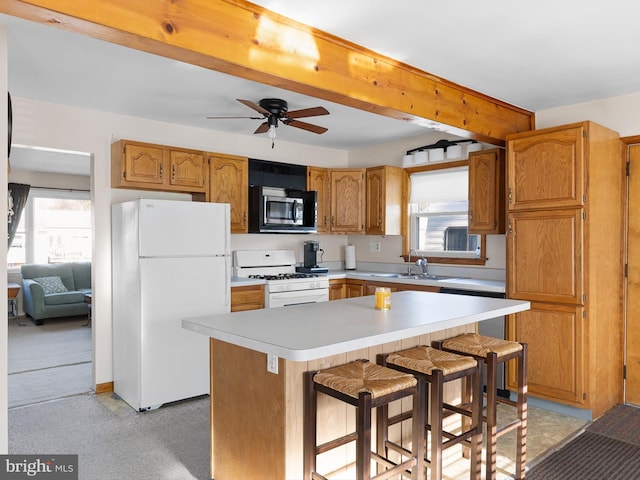 kitchen featuring white appliances, a kitchen island, a sink, light countertops, and beamed ceiling