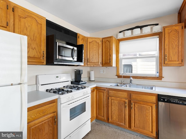 kitchen featuring brown cabinets, stainless steel appliances, a sink, and light countertops