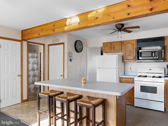 kitchen featuring white appliances, beamed ceiling, and a breakfast bar area