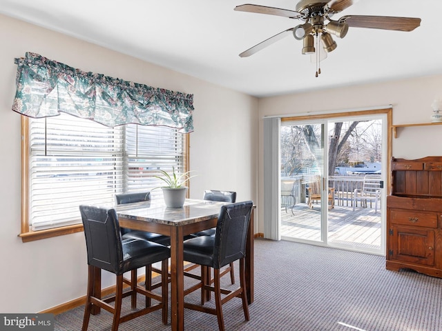 carpeted dining space featuring baseboards and a ceiling fan