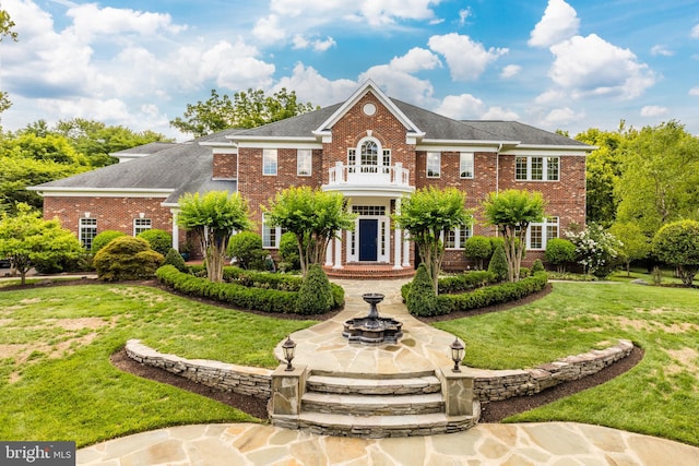 colonial inspired home featuring a front lawn and a balcony