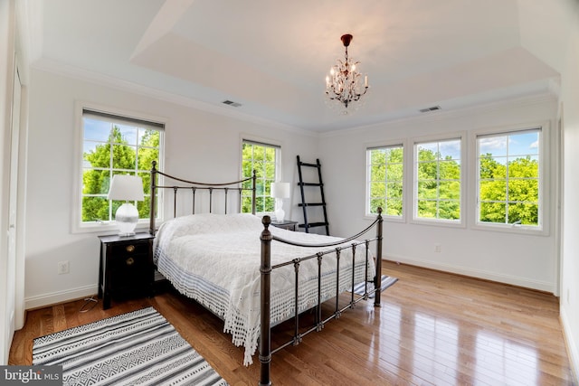 bedroom with wood-type flooring, multiple windows, and a notable chandelier