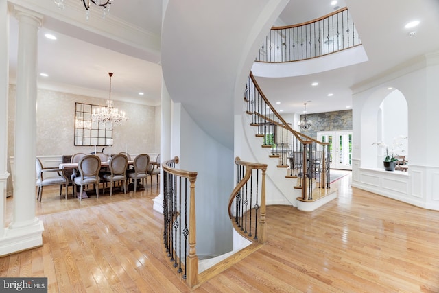 stairs featuring wood-type flooring, crown molding, and a notable chandelier