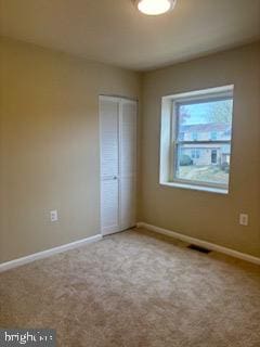 unfurnished bedroom with a closet and light colored carpet