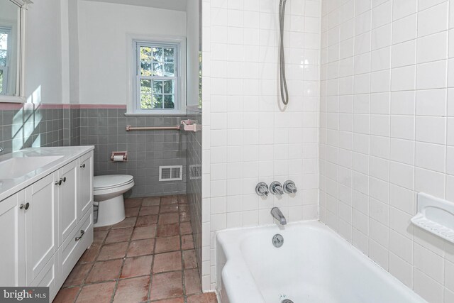 339 Hamilton Ave, Princeton, NJ 08540 - bathroom featuring tile walls, toilet, vanity,  shower combination, and a wainscoted wall