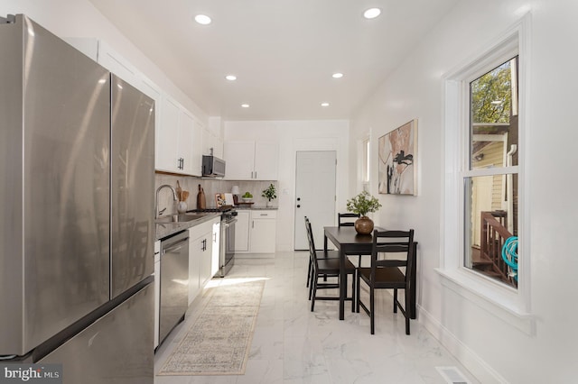 kitchen featuring tasteful backsplash, white cabinetry, sink, and stainless steel appliances