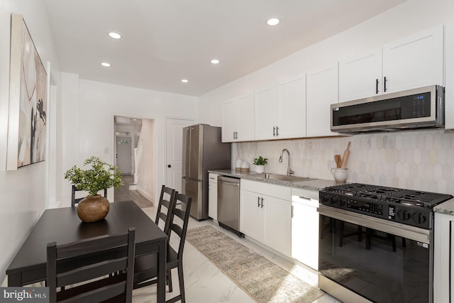 kitchen with stainless steel appliances, white cabinetry, sink, and tasteful backsplash