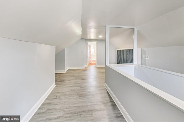 corridor featuring light hardwood / wood-style flooring and vaulted ceiling