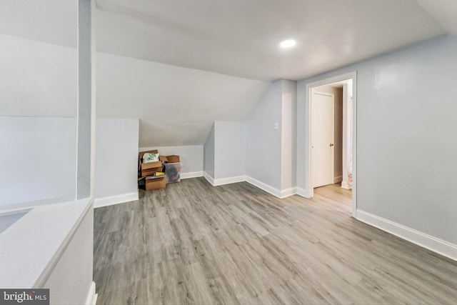 additional living space with light wood-type flooring and vaulted ceiling