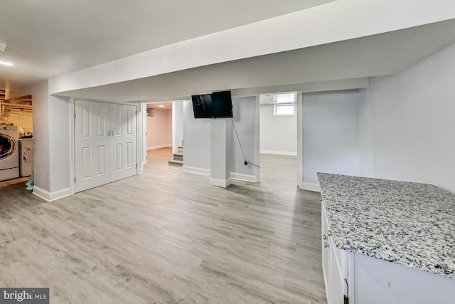 basement with light hardwood / wood-style floors and washer and dryer