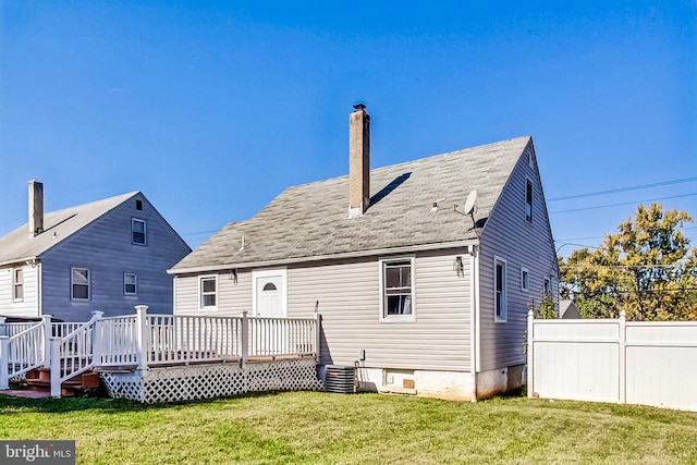 back of property featuring a lawn and a deck