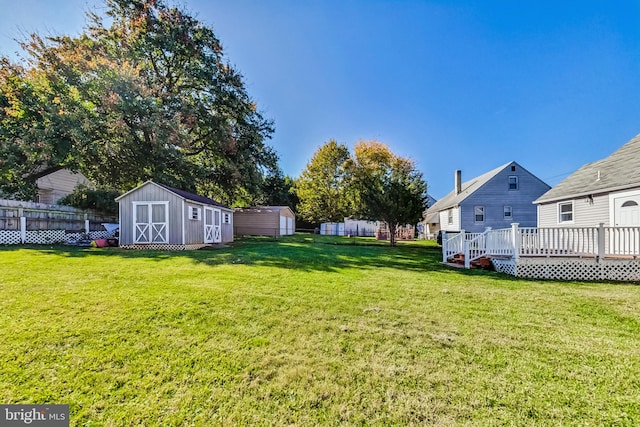 view of yard featuring a wooden deck and a storage shed