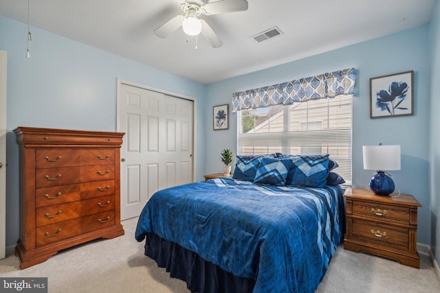 bedroom featuring light colored carpet, ceiling fan, and a closet