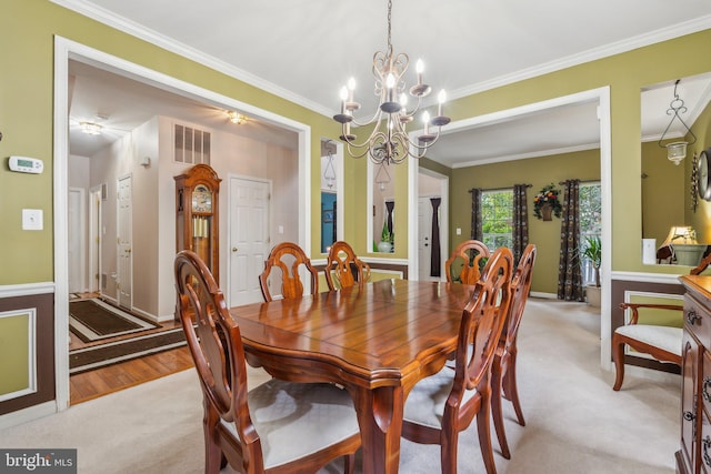 dining space featuring light wood-type flooring, a notable chandelier, and crown molding