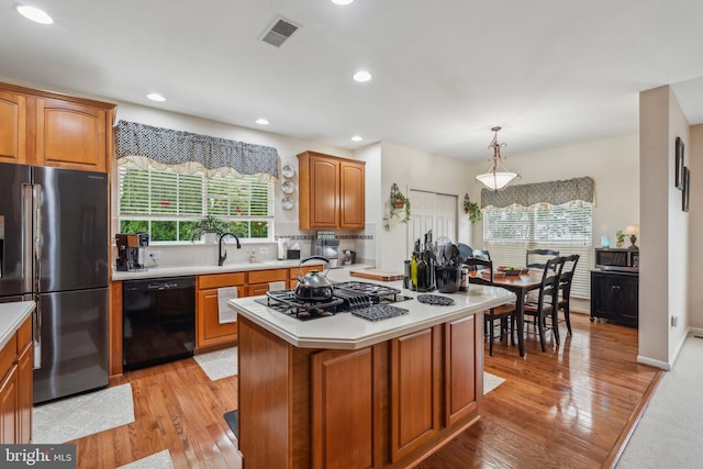 kitchen featuring pendant lighting, a kitchen island, light hardwood / wood-style flooring, and appliances with stainless steel finishes