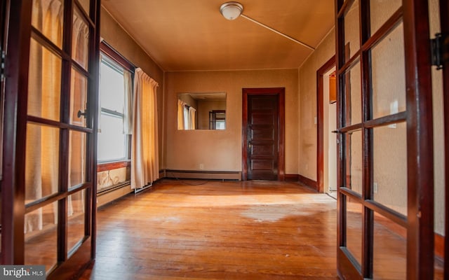 hallway with baseboard heating, french doors, and light hardwood / wood-style flooring