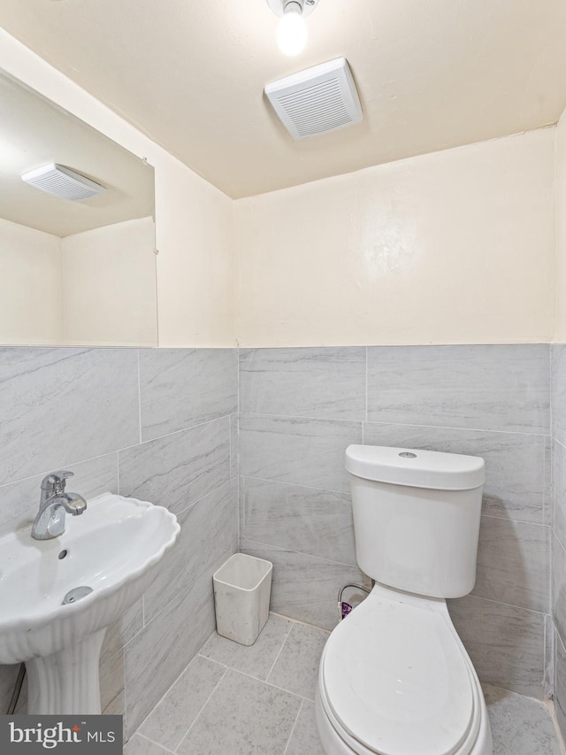 bathroom featuring tile patterned floors, tile walls, and toilet