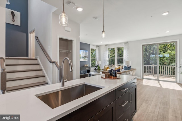 kitchen featuring light wood-type flooring, hanging light fixtures, and sink