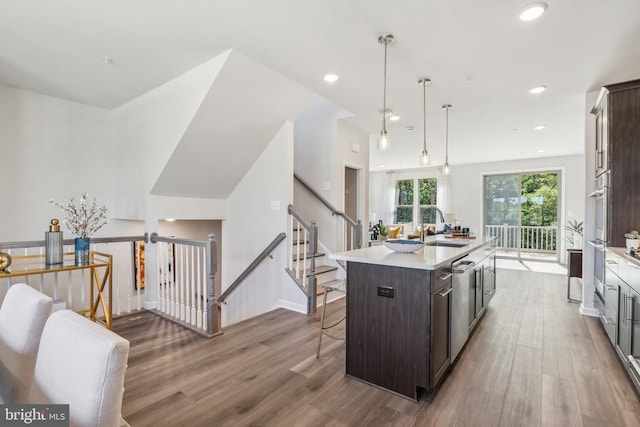 kitchen featuring pendant lighting, dark brown cabinets, a kitchen island with sink, and hardwood / wood-style floors