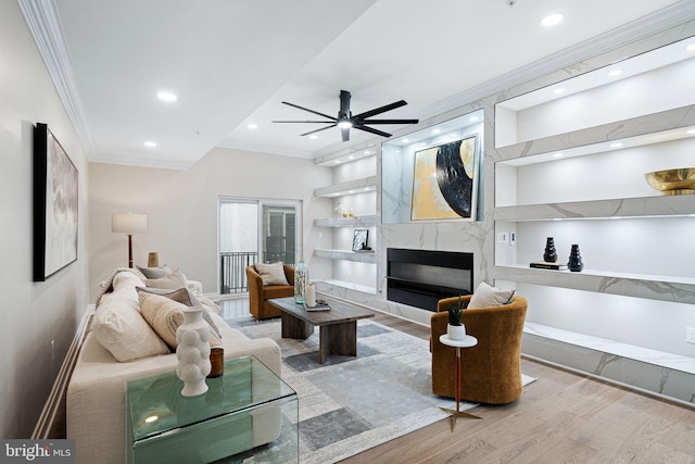 living room featuring a fireplace, hardwood / wood-style flooring, crown molding, and ceiling fan