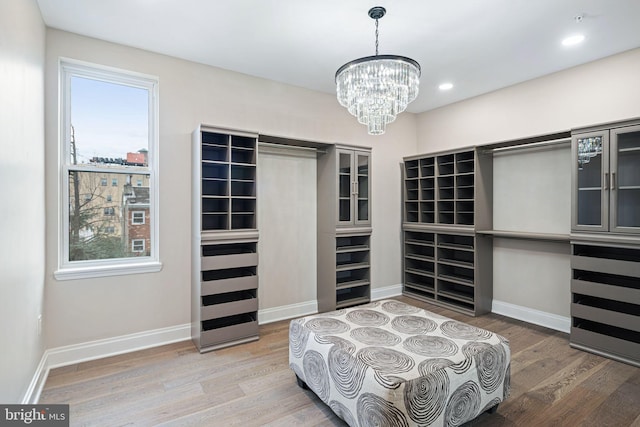 walk in closet with an inviting chandelier and wood-type flooring