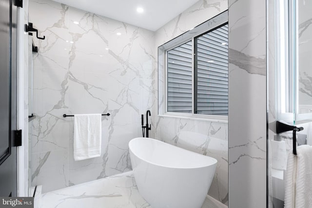 bathroom featuring a bathtub and tile walls