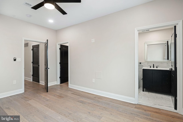 unfurnished bedroom with ceiling fan, connected bathroom, sink, and light wood-type flooring