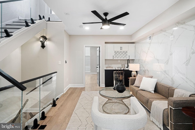 living room with ceiling fan, tile walls, and light hardwood / wood-style floors