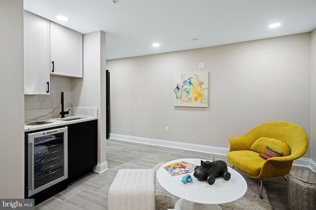 kitchen with wine cooler, sink, light hardwood / wood-style floors, and white cabinets