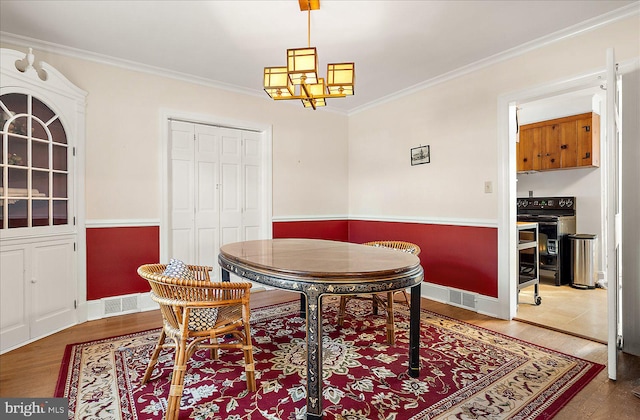 dining space featuring an inviting chandelier, hardwood / wood-style floors, and ornamental molding