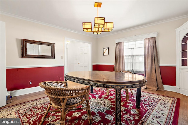 dining area with hardwood / wood-style floors, crown molding, and a notable chandelier