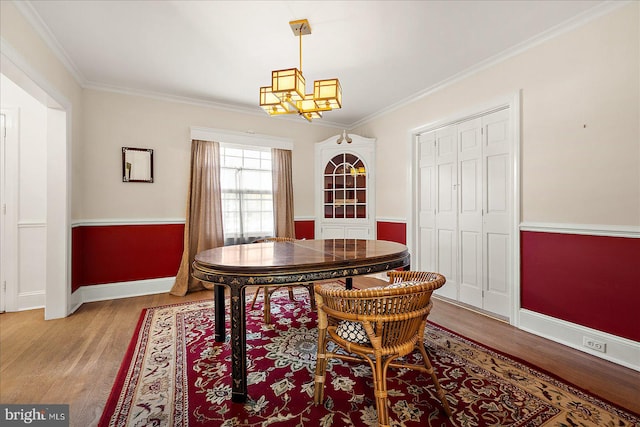 dining room featuring light wood-type flooring, a notable chandelier, and crown molding