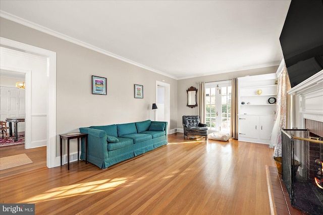 living room featuring a fireplace, wood-type flooring, and crown molding