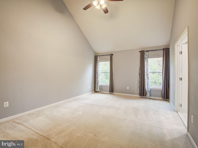 empty room featuring light carpet, high vaulted ceiling, a ceiling fan, and baseboards