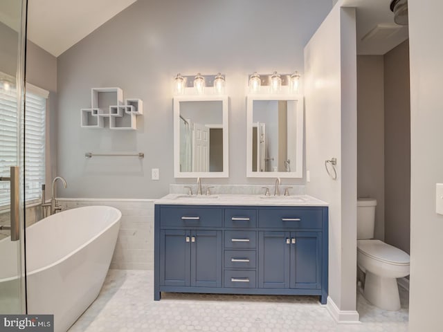 full bath with vaulted ceiling, a sink, a freestanding bath, and toilet