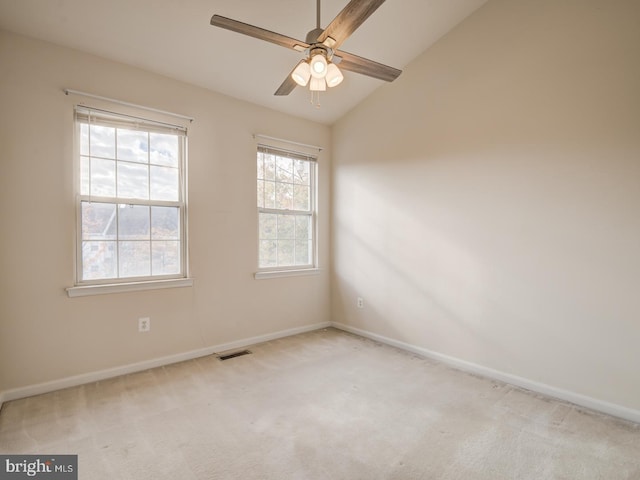 carpeted empty room with vaulted ceiling, a ceiling fan, and baseboards