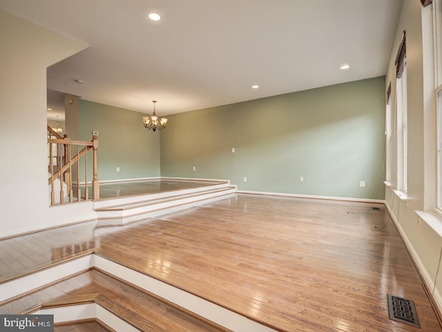 spare room with baseboards, visible vents, wood finished floors, an inviting chandelier, and recessed lighting