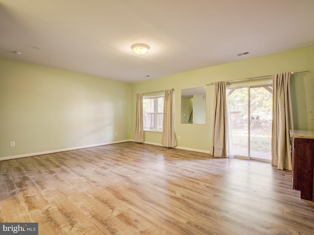 unfurnished room featuring baseboards, visible vents, and wood finished floors