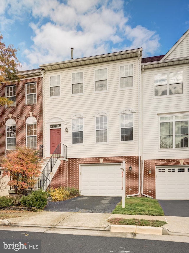 multi unit property featuring brick siding, driveway, and an attached garage