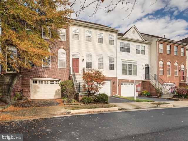 townhome / multi-family property with a garage, brick siding, and aphalt driveway