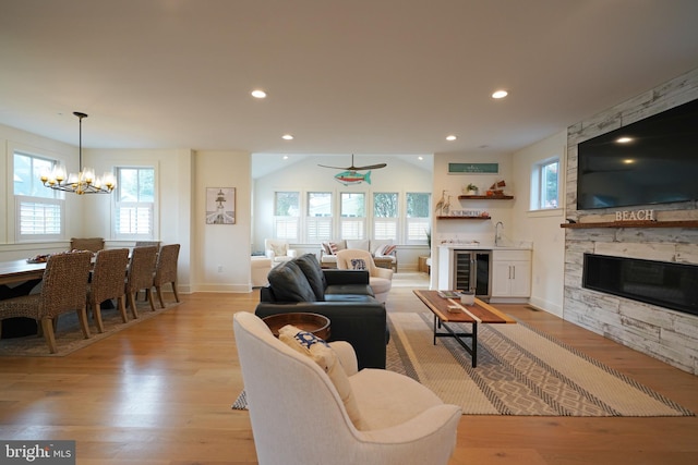 living room featuring a stone fireplace, light hardwood / wood-style flooring, a healthy amount of sunlight, and wine cooler