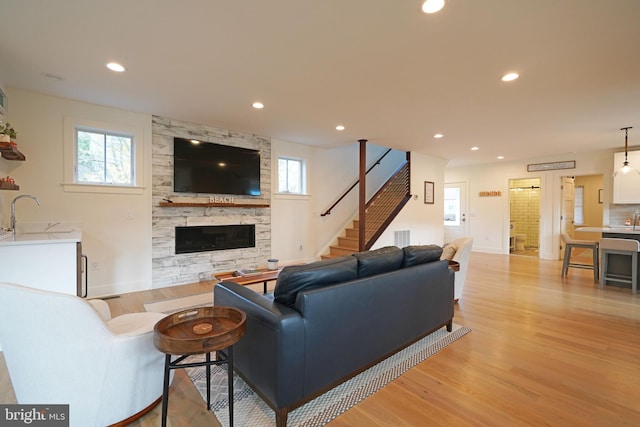 living room with a fireplace, sink, light hardwood / wood-style floors, and plenty of natural light