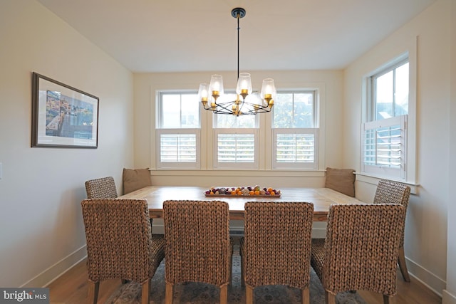 dining space with hardwood / wood-style floors and a notable chandelier