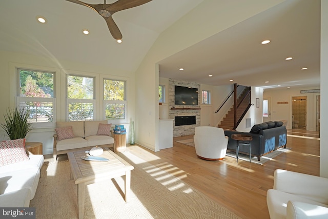 living room featuring a fireplace, light hardwood / wood-style flooring, lofted ceiling, and ceiling fan