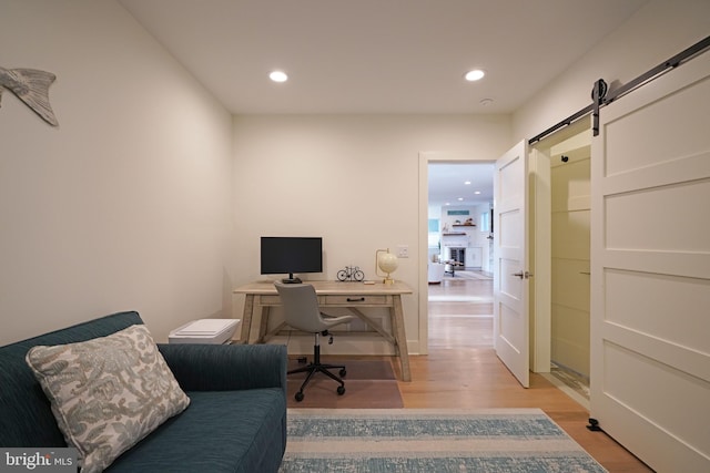 office with light wood-type flooring and a barn door