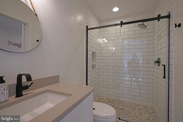 bathroom featuring a shower with door, vanity, and toilet