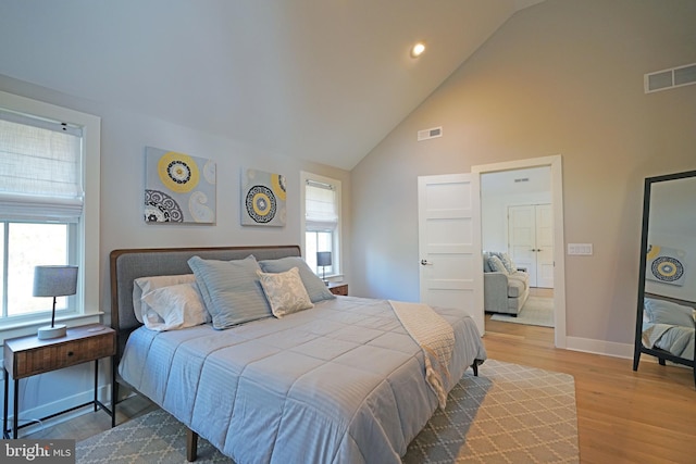 bedroom featuring hardwood / wood-style flooring, high vaulted ceiling, and multiple windows